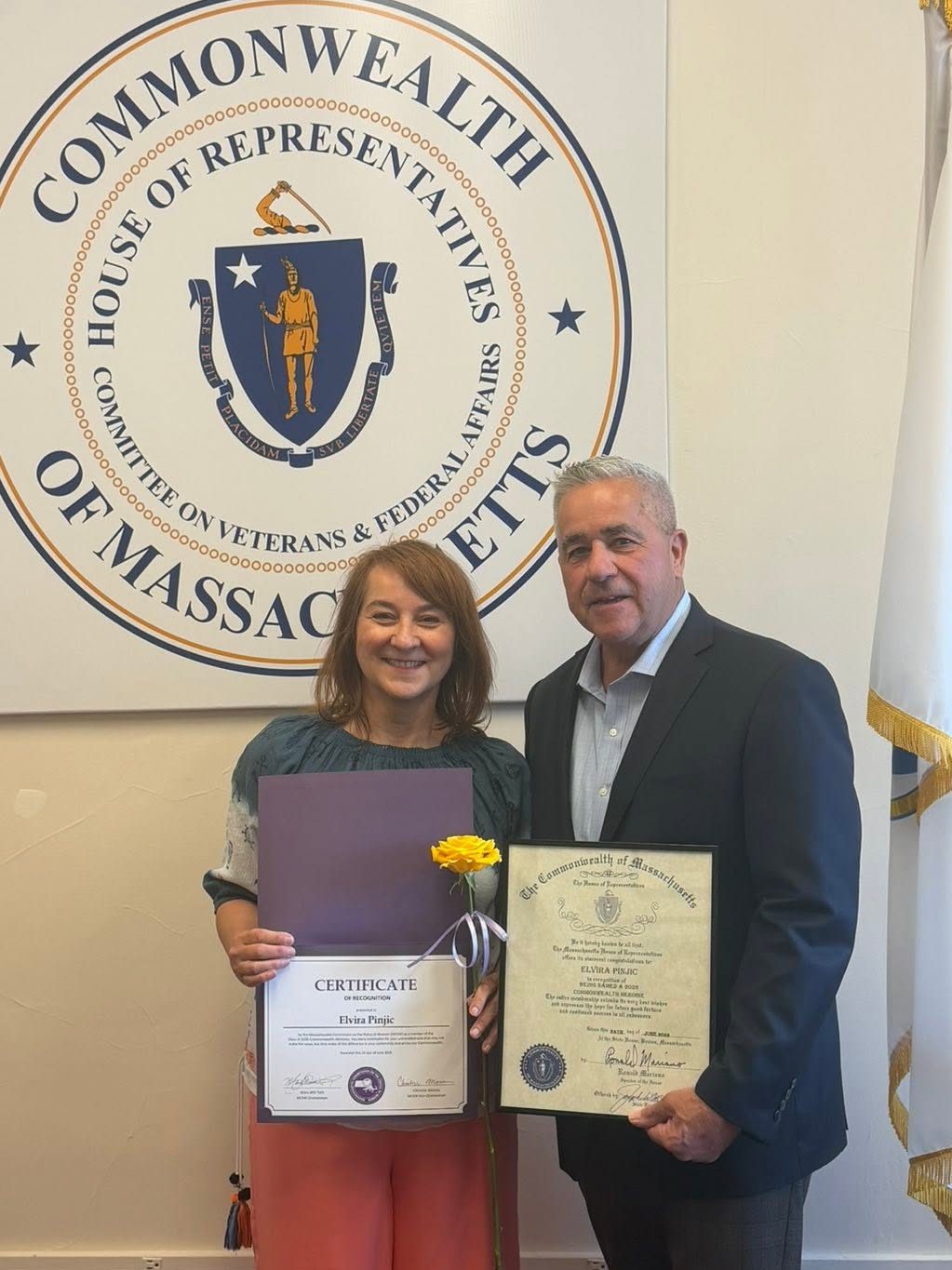 Executive Director Elvira Pinjic smiles while holding her certificate with Rep. McGonagle who holds an official House citation for her.